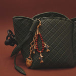 Green quilted handbag with decorative fish keychain on a brown background