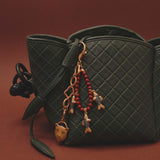 Green quilted handbag with decorative fish keychain on a brown background