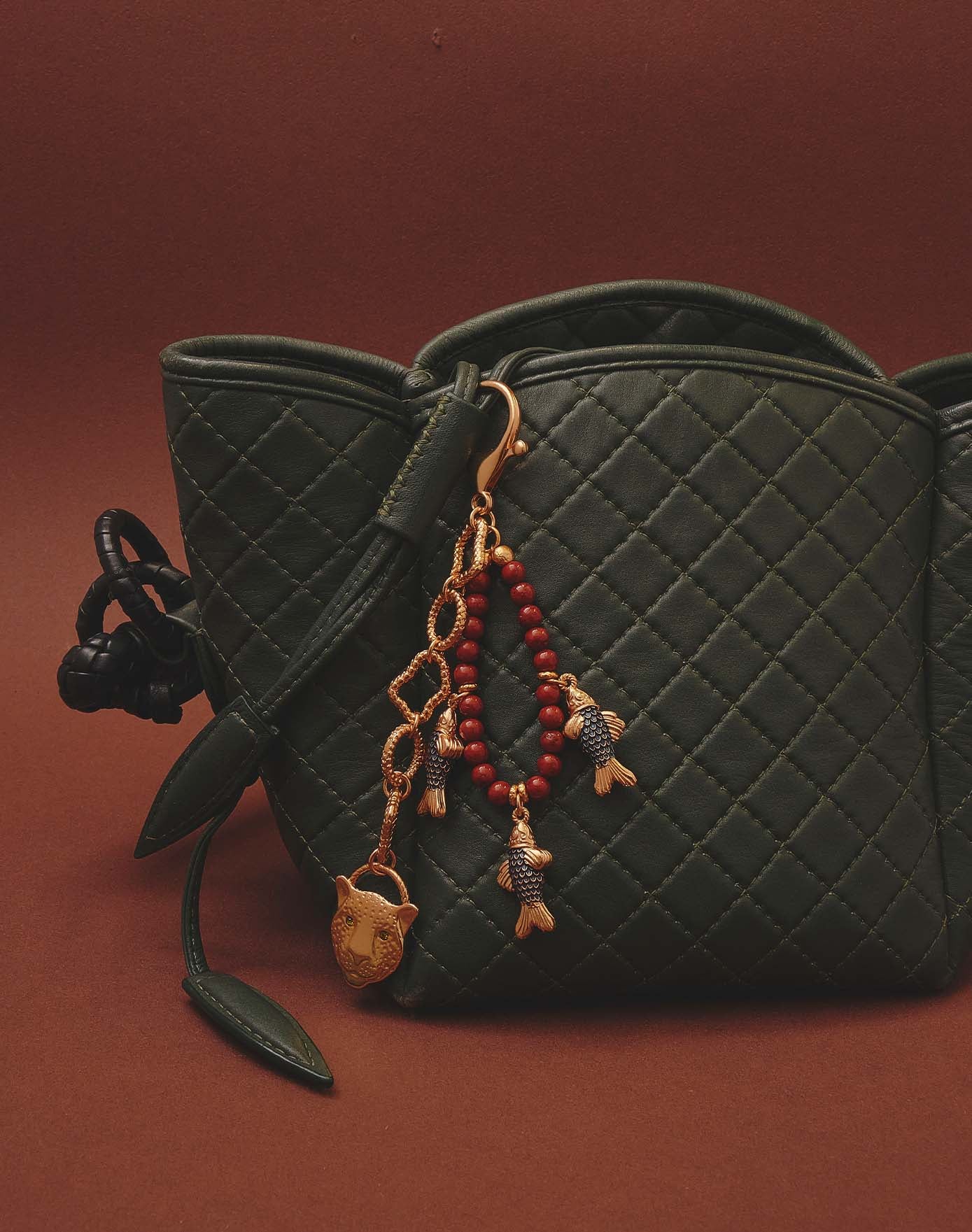 Green quilted handbag with decorative fish keychain on a brown background