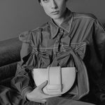 Person holding a handbag in a black and white setting.