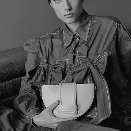 Person holding a handbag in a black and white setting.