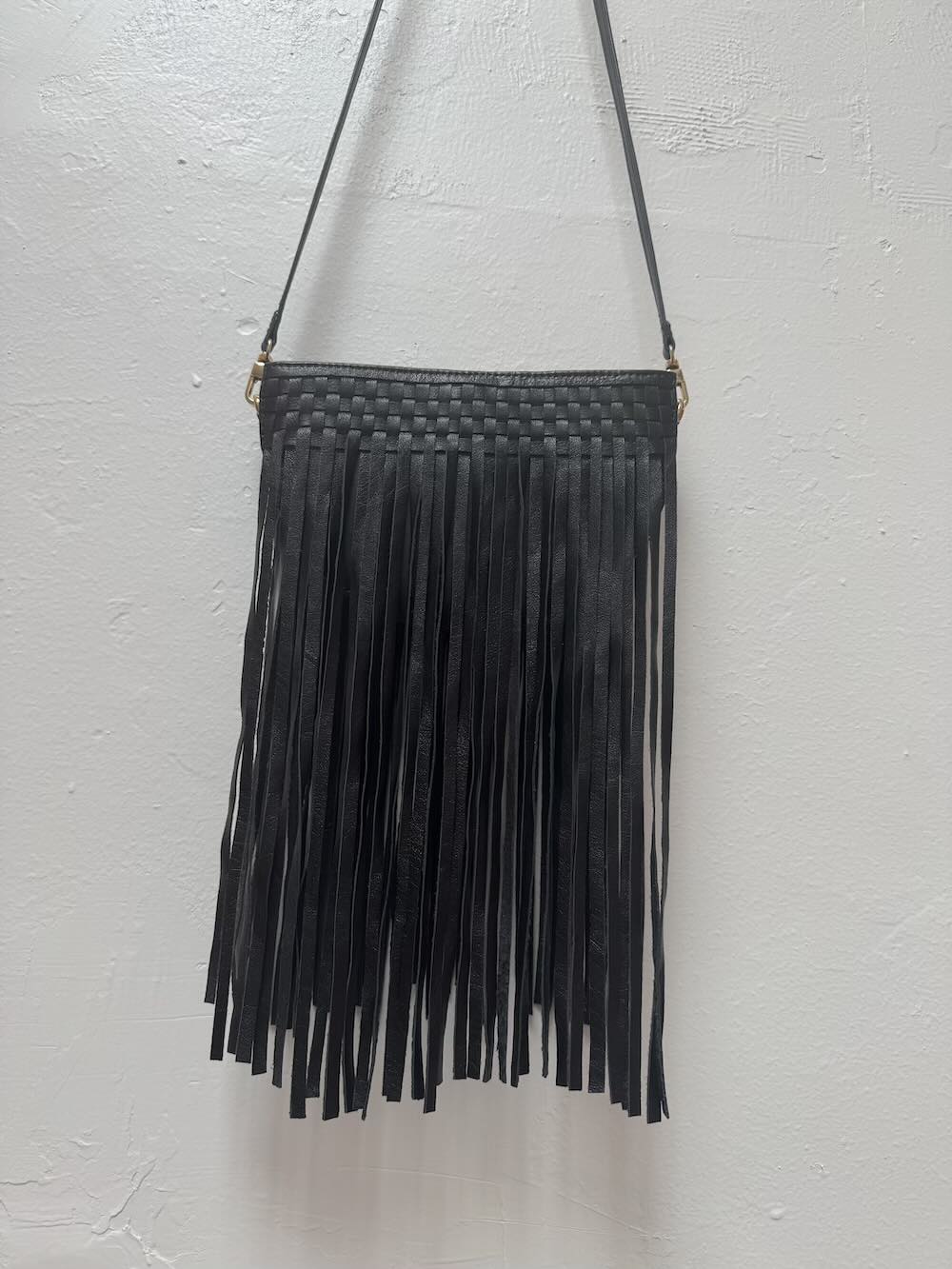 Black fringed handbag on a white background.