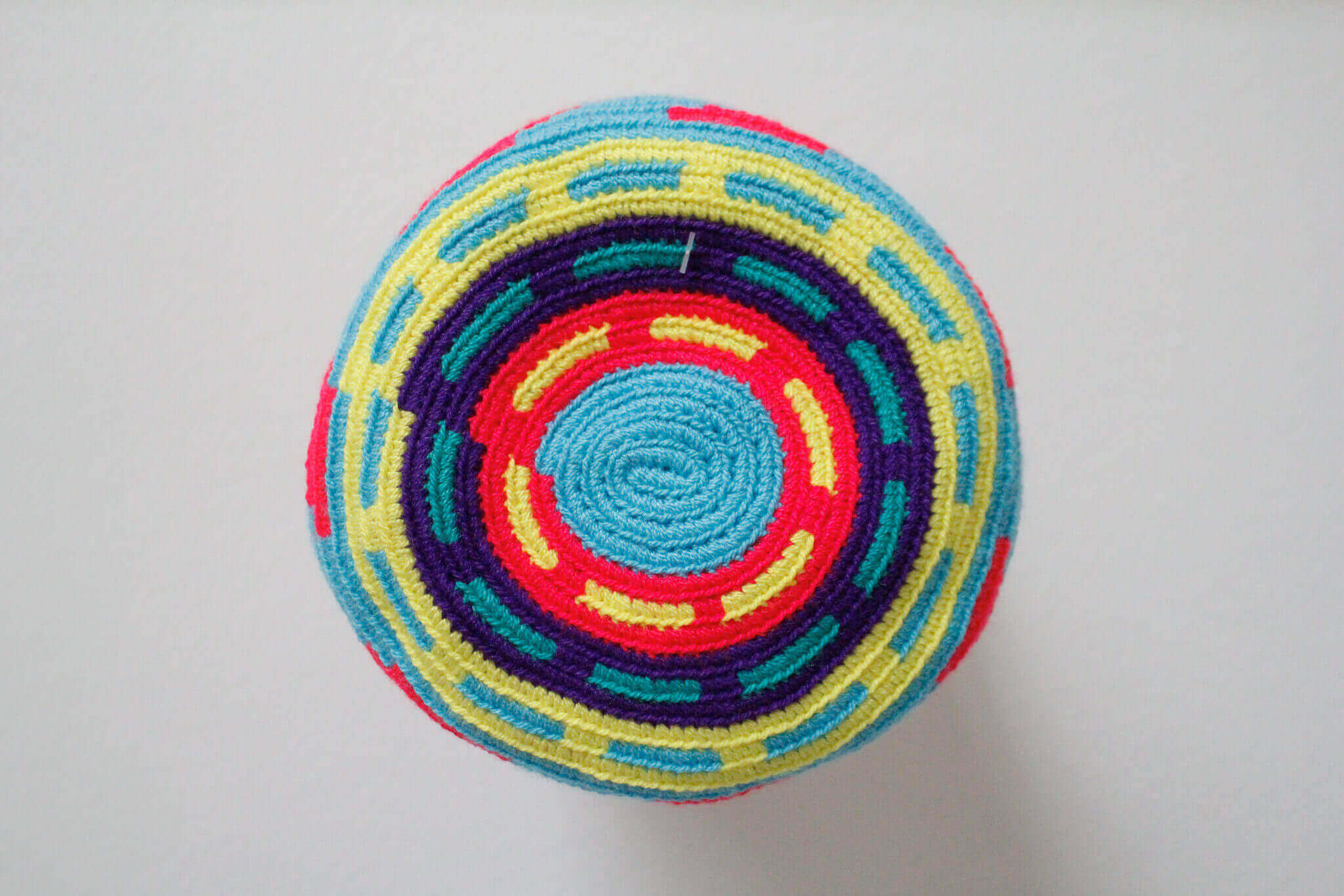 A small handmade Wayuu crossbody bag with a geometric pattern, featuring a wide woven strap and a flat tassel closure.