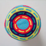 A small handmade Wayuu crossbody bag with a geometric pattern, featuring a wide woven strap and a flat tassel closure.