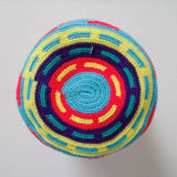 A small handmade Wayuu crossbody bag with a geometric pattern, featuring a wide woven strap and a flat tassel closure.