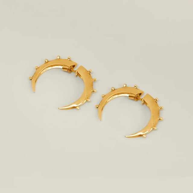Gold crescent hoop earrings with small studs on a light gray background.