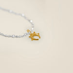Gold horse shoe charm on a silver chain against a beige background