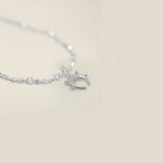 Small sterling silver horseshoe pendant with sphere detail on a neutral background