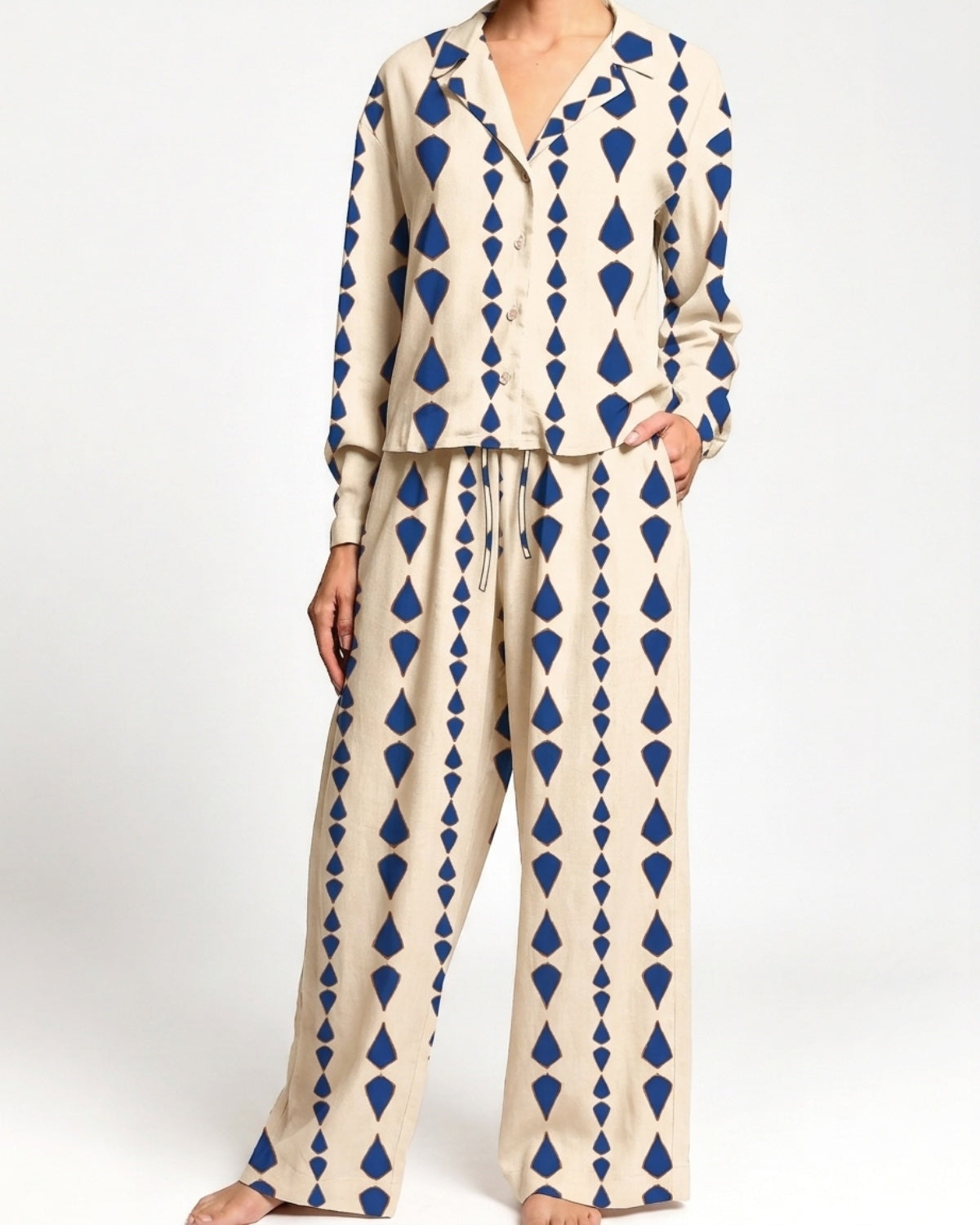 A woman modeling a two-piece set with a beige base and a blue geometric diamond pattern, featuring a long-sleeve button-up top and matching wide-leg pants.
