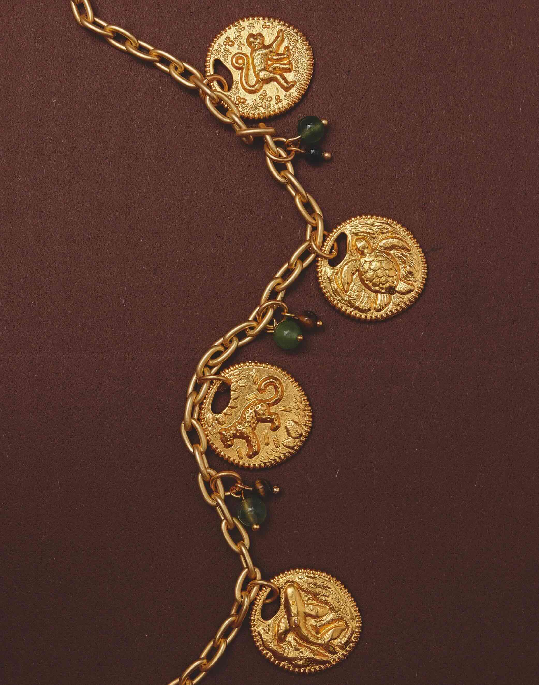 Gold necklace with animal charm pendants on a brown background