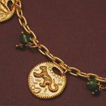 Close up of a necklace with a lion charm and green beads on a dark background