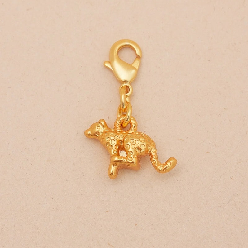 Gold cheetah-shaped charm on a beige background