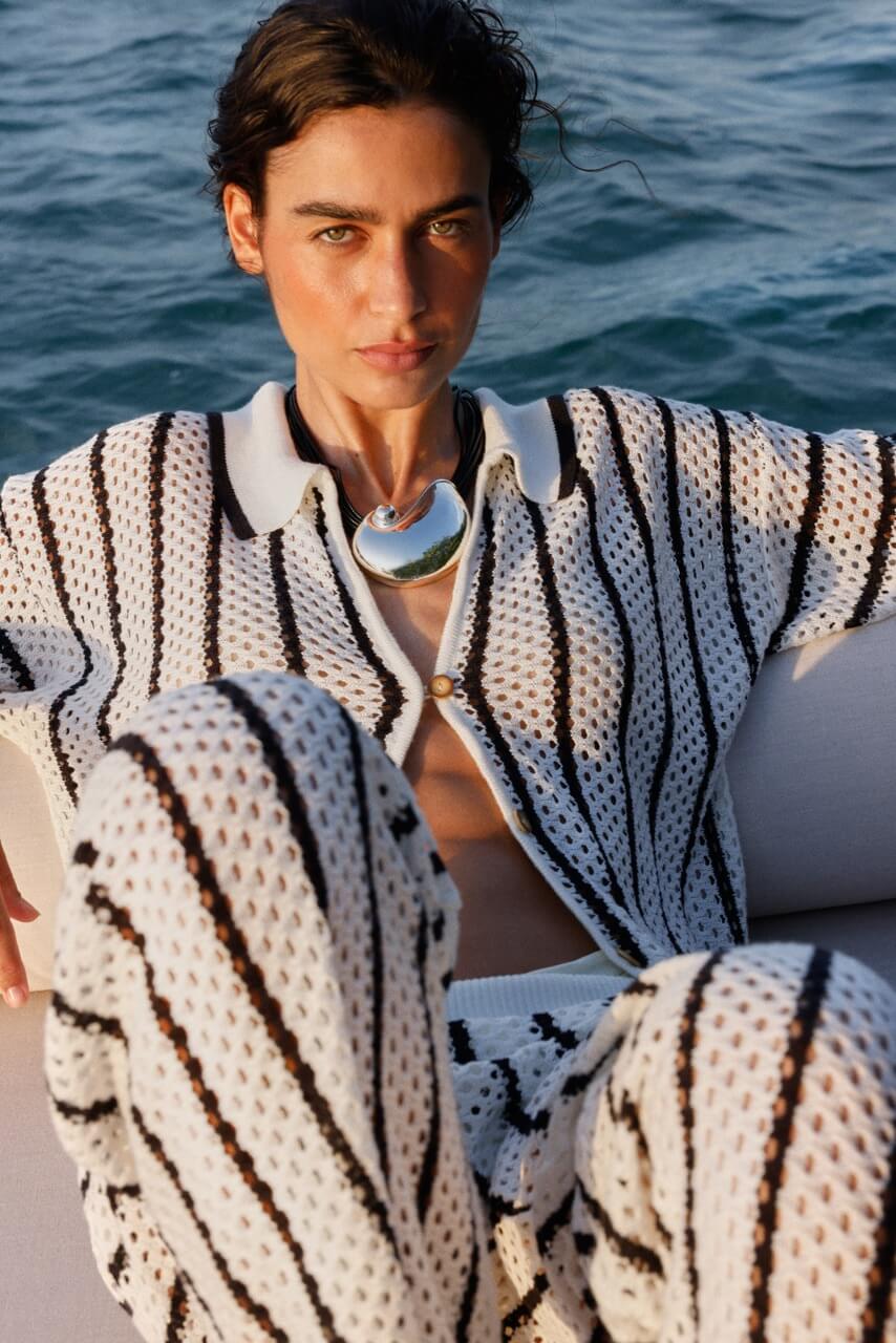 A woman wearing a black and white patterned outfit with a scenic background.