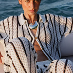 A woman wearing a black and white patterned outfit with a scenic background.