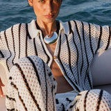 A woman wearing a black and white patterned outfit with a scenic background.