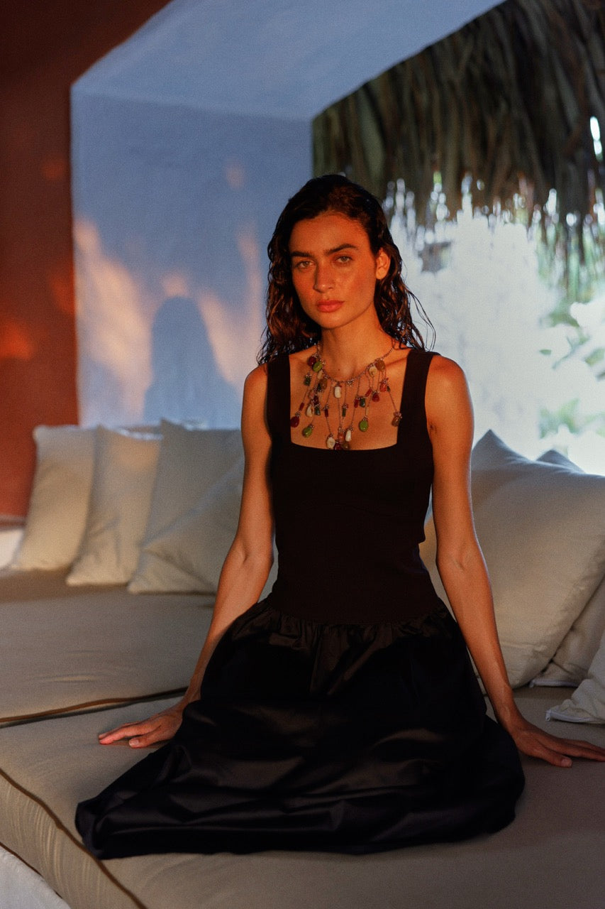 Woman in a black dress sitting on a couch with a blurred background.
