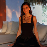 Woman in a black dress sitting on a couch with a blurred background.