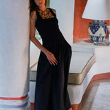 Woman in a black dress standing in a room with a white column and a lamp.