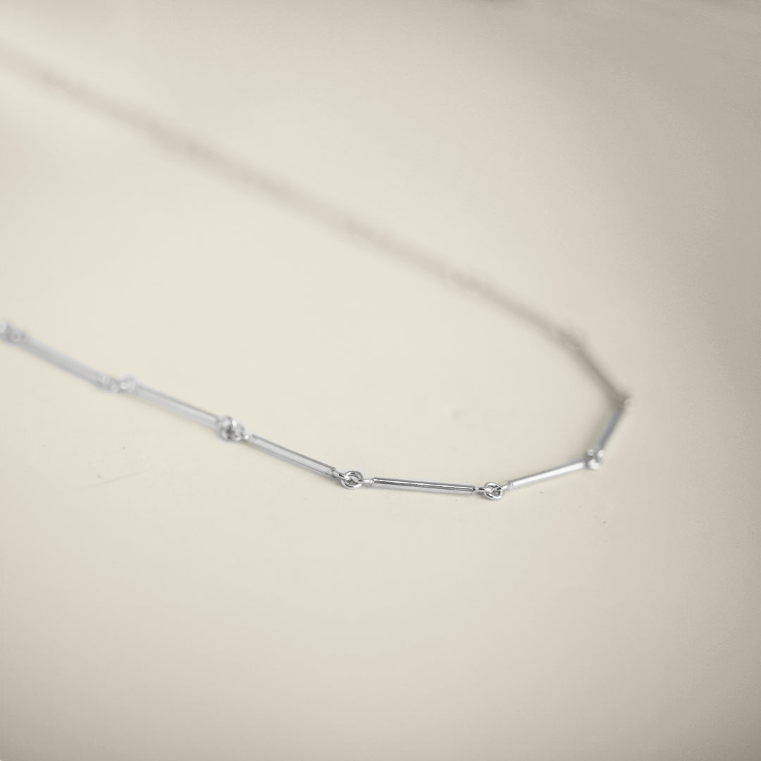 Silver necklace on a light beige background