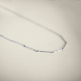 Silver necklace on a light beige background