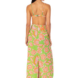 Woman wearing a green floral dress with a white background.