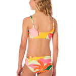 Young girl wearing a colorful floral bikini set on a white background.
