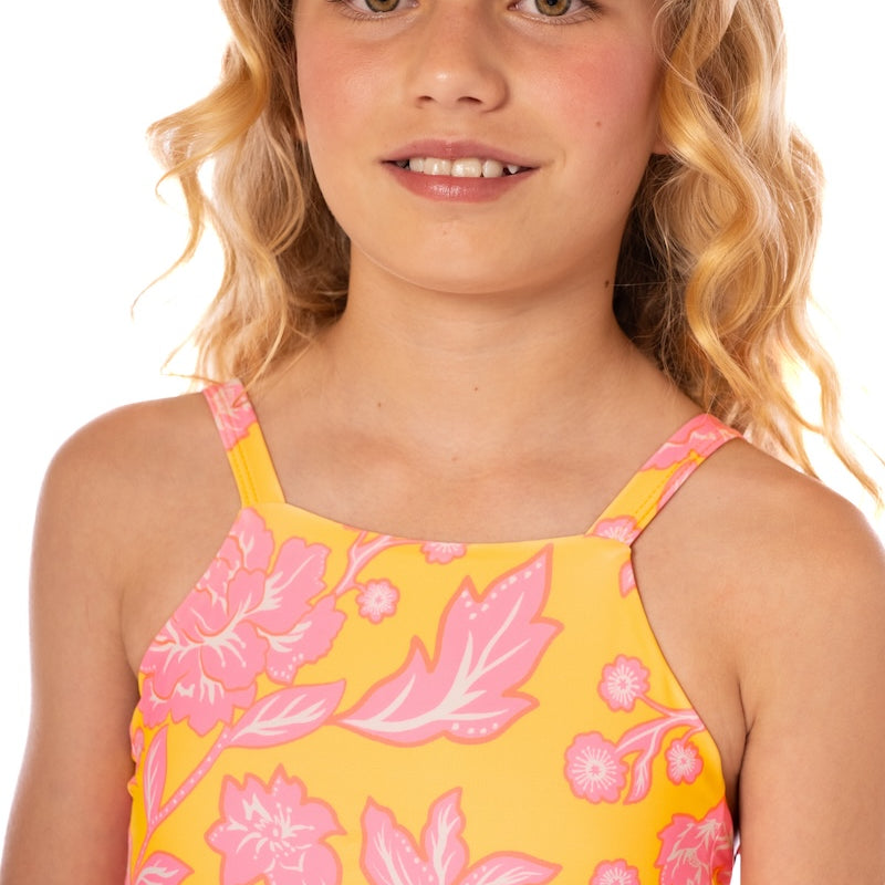Young girl wearing a yellow floral dress with pink flowers on a white background.