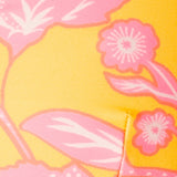 Close-up of a yellow fabric with pink floral patterns.