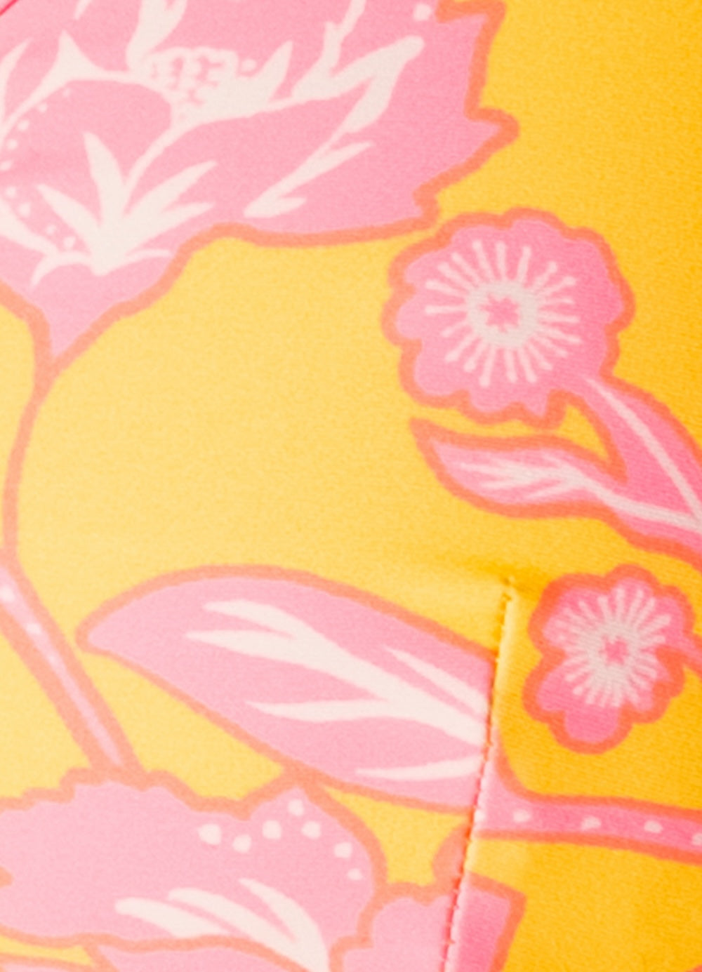 Close-up of a yellow fabric with pink floral patterns.