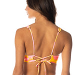 Woman wearing a colorful bikini with pink and yellow straps on a white background.