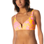 Woman wearing a yellow and pink floral bikini on a white background.