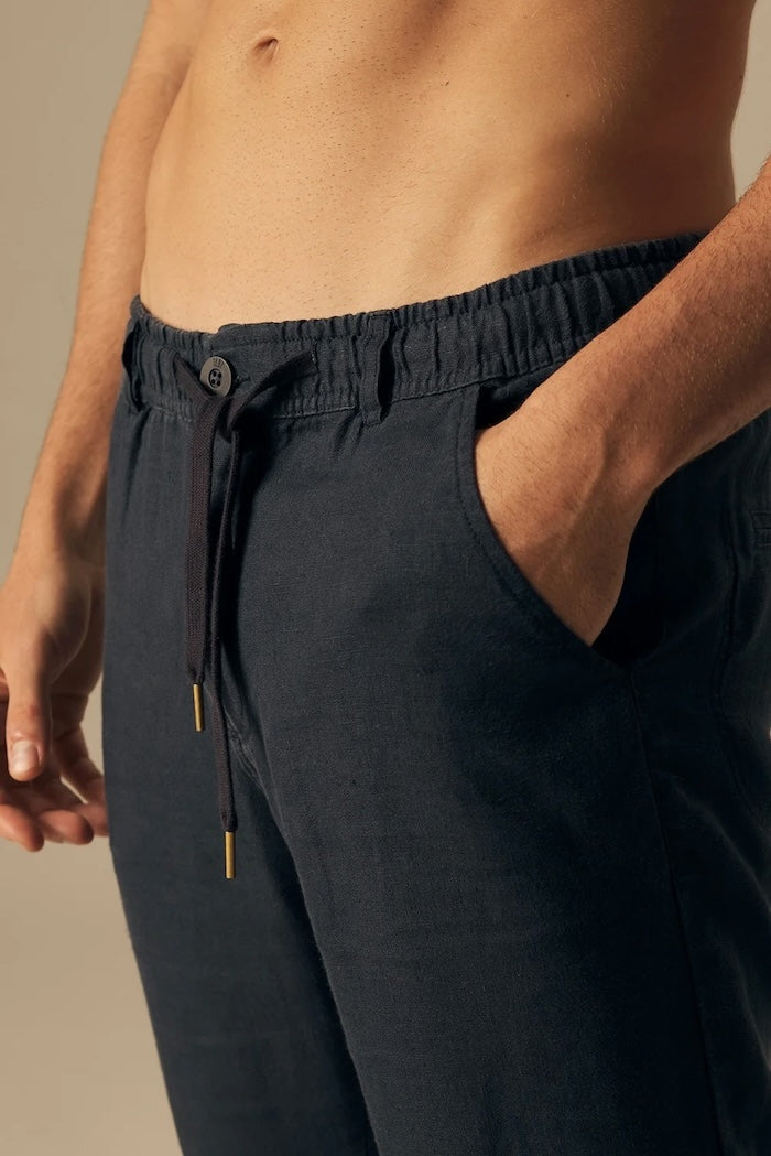 Navy blue pants worn by a person on a beige background.