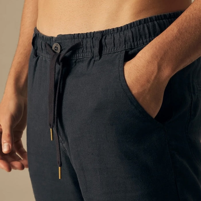 Navy blue pants worn by a person on a beige background.