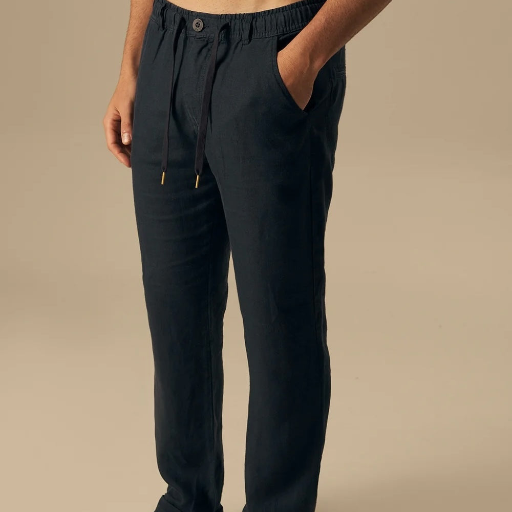 Man wearing dark blue pants on a beige background.