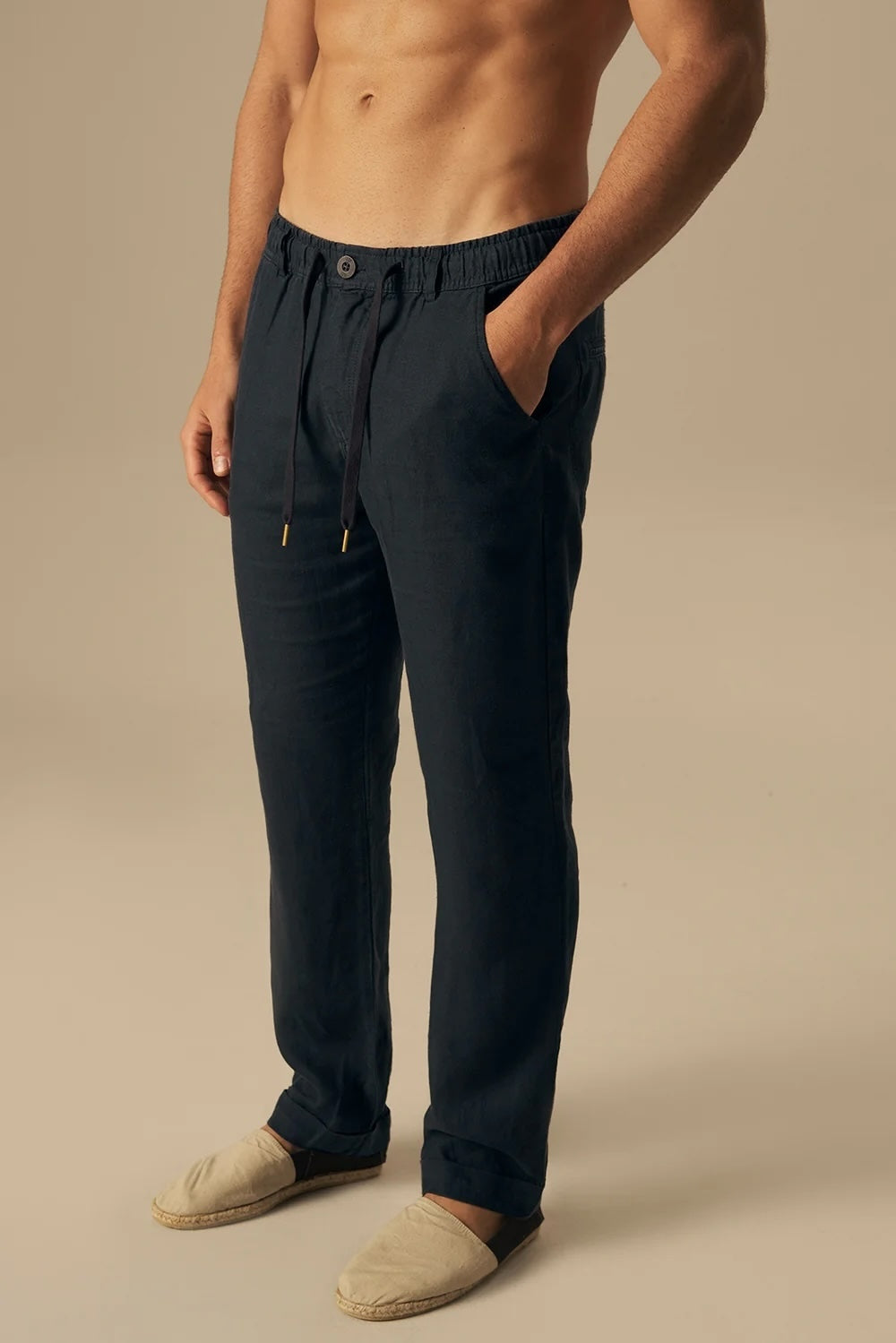 Man wearing dark blue pants on a beige background.