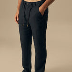 Man wearing dark blue pants on a beige background.