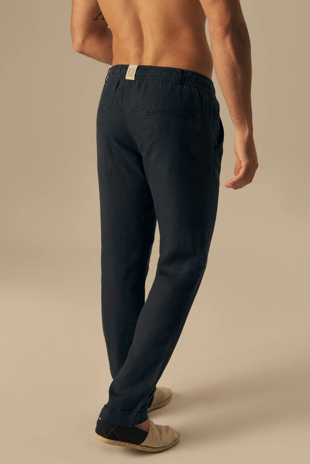 Person wearing navy blue pants on a beige background.