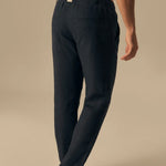 Person wearing navy blue pants on a beige background.
