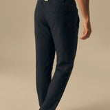 Person wearing navy blue pants on a beige background.