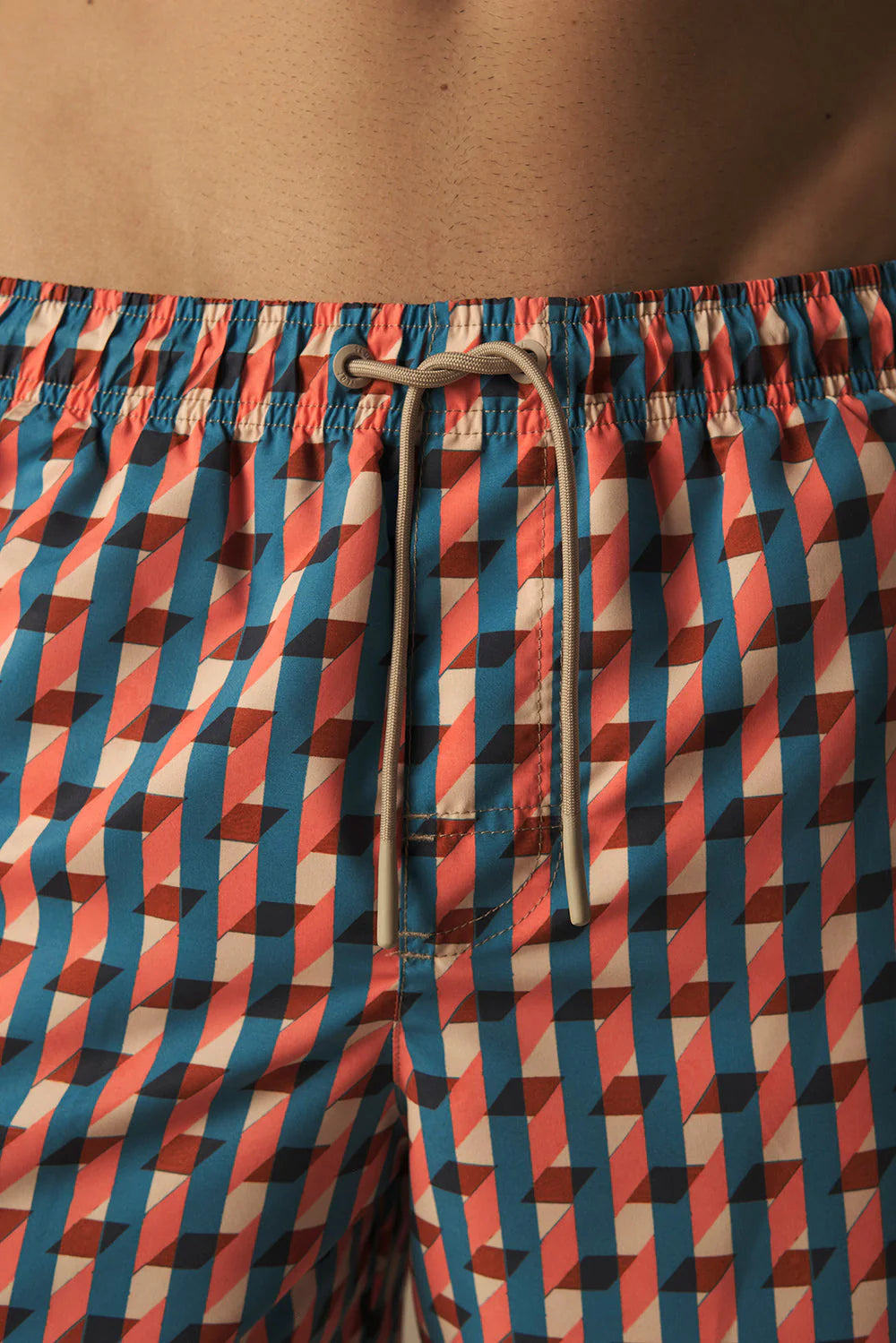 Geometric patterned swim shorts with a drawstring on a plain background.