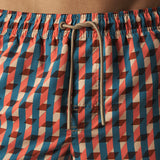 Geometric patterned swim shorts with a drawstring on a plain background.