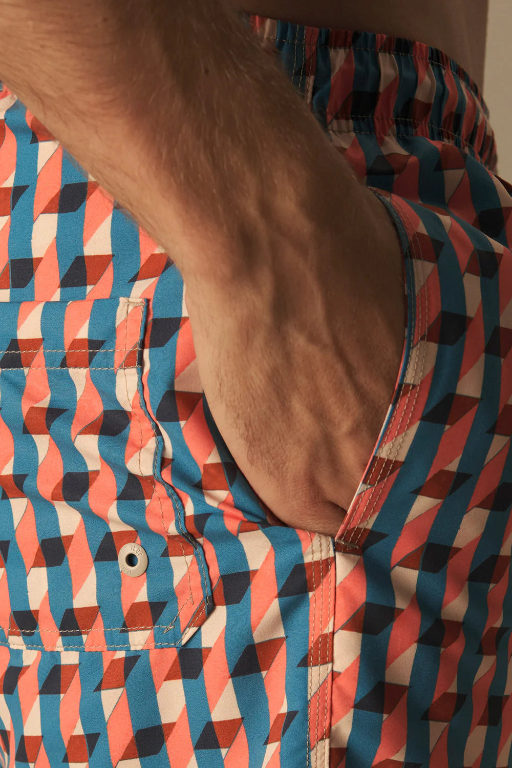 Close-up of a person wearing a colorful geometric patterned swim shorts.