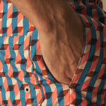 Close-up of a person wearing a colorful geometric patterned swim shorts.