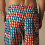 Person wearing a patterned swim shorts on a beige background.