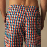 Person wearing a patterned swim shorts on a beige background.