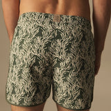 Man wearing green swim trunks neutral leaf pattern. 