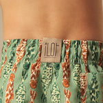 Green and orange fish-patterned swim shorts with a visible brand label on a person wearing them.
