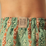 Green and orange fish-patterned swim shorts with a visible brand label on a person wearing them.