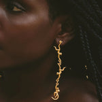 Close-up of a person wearing gold earrings with a dark background