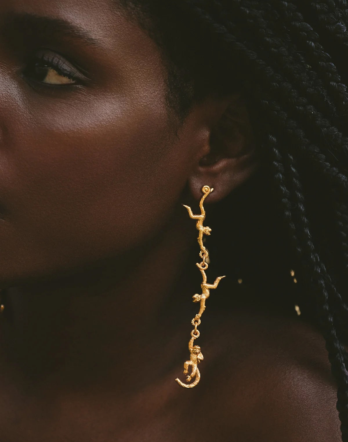 Close-up of a person wearing gold earrings with a dark background